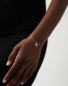 Elegant 18K silver bracelet with shimmering cross pendant on a female wrist