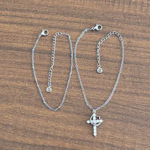 Detailed silver satellite chain and cross pendant with zircon stones on wood surface