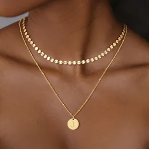 Primer plano de collar de doble capa de oro 18K con colgante de disco y letra J