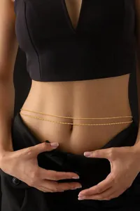 Detail of layered gold stainless steel waist chain on model with sleek beads and twist links
