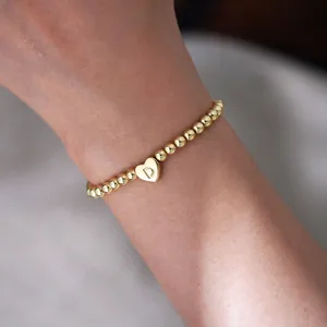 Detail of 18K gold plated bead bracelet with heart pendant featuring an engraved letter D