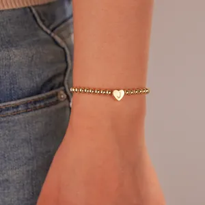 Macro view of gold stainless steel beaded bracelet with letter J heart pendant