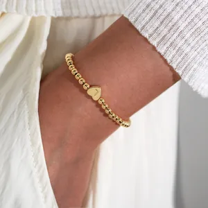 Detail of 18K gold-plated beaded bracelet with heart charm engraved with the letter L