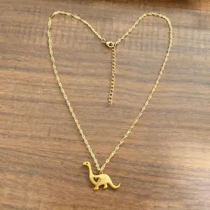 Golden dinosaur pendant necklace with hollow heart detail on wooden background
