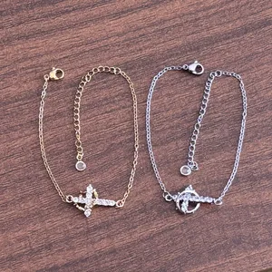 Detail of gold and silver planetary cross bracelets with sparkling cubic zirconia pavé