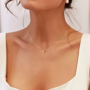 Vista dettagliata di una collana minimalista con croce d'oro sul collo della modella