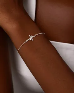 Close-up of a 18K silver bracelet with 3A zircon crown and cross charms on a model wrist