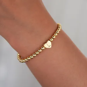 Detail of 18K gold plated bead bracelet featuring a heart pendant with the letter L