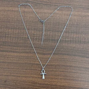 Dettaglio del ciondolo Ankh argento con catena regolabile su superficie di legno