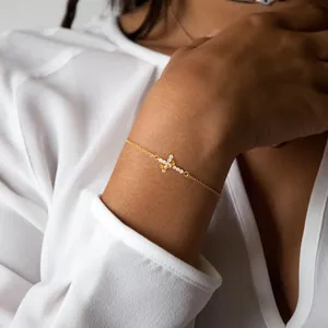Close-up of a 18K gold bracelet with cross crown charms and cubic zirconia on a wrist