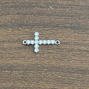 Macro shot of silver cross charm with micro-paved zircons and dual connection rings