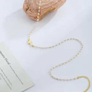 Detail of gold cross pendant on a pearl chain necklace with an adjustable extender chain