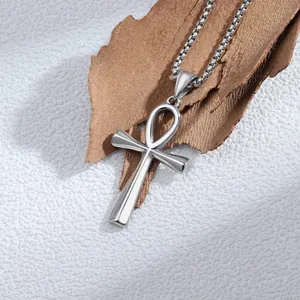 Dettaglio di un ciondolo Ankh in argento appoggiato su uno sfondo di corteccia rustica