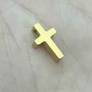 Vista macro del mini ciondolo a croce placcato oro 18K con finitura metallica liscia