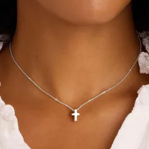 Dettaglio di una collana con ciondolo a piccola croce in acciaio inox argento su modella