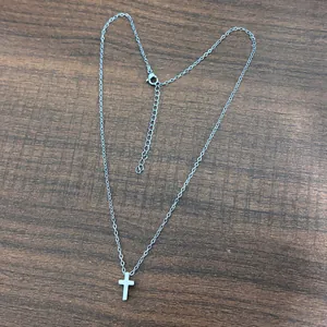 Dettaglio macro della collana con croce in acciaio inossidabile e chiusura a moschettone