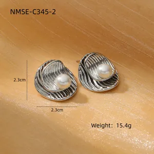 Macro detail of 30mm C-shaped brushed titanium earrings with shell texture and pearl