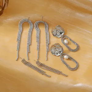 Set de pendientes plateados de lujo con diseño de borlas y perlas sobre fondo de seda dorada