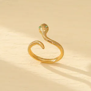 Gros plan d'une bague serpent dorée avec des yeux en pierres vertes et texture d'écailles