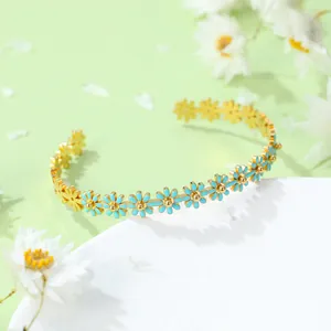 Détail d'un jonc marguerite doré avec émail bleu ciel sur un fond vert pastel élégant