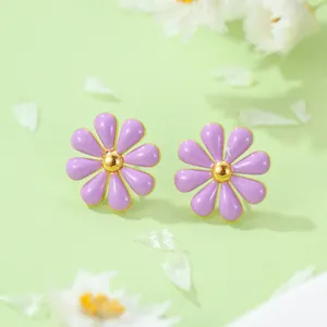 Vue macro de boucles d'oreilles marguerites mauves au centre doré sur fond vert doux
