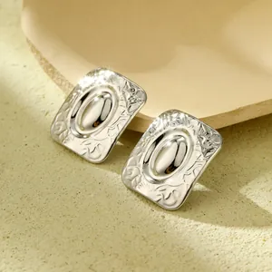 Détail macro de boucles d'oreilles rectangulaires en argent avec motifs floraux