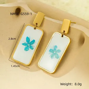 Gold rectangular drop earrings featuring blue dried flower patterns and geometric studs