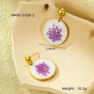 Detailed view of round gold stainless steel earrings with purple dried flowers inside