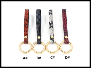 Detail view of four colored faux snake leather keyrings with gold metallic buckles
