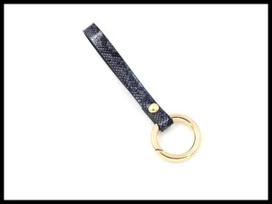 Detail of black faux snakeskin leather strap with golden circular spring ring clasp