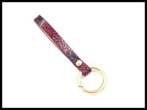 Close-up of red and black snakeskin pattern leather strap with gold metal spring ring