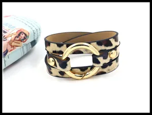 Detail eines Wickelarmbands aus Leder mit Leopardenmuster und großer goldener Schnalle