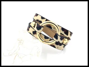 Detail eines mehrlagigen Armbands mit Leopardenmuster, Goldringen und Nietenbesatz