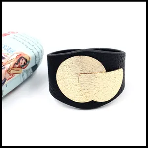 Detail van brede zwarte kunstlederen armband met getextureerde gouden metalen delen