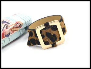 Detalle de textura de leopardo en pelo y hebilla dorada en pulsera ancha de puño