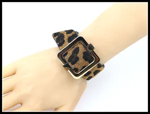 Detalle de brazalete ancho con estampado de leopardo y hebilla cuadrada dorada