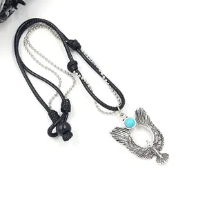 Detail view of retro eagle pendant with turquoise stone and braided metal chain