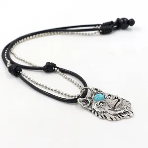 Detail of silver wolf head pendant necklace with turquoise bead and double-layer chain