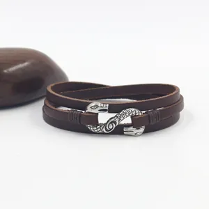 Detail of vintage snake motif silver charm on multi-layer brown leather bracelet