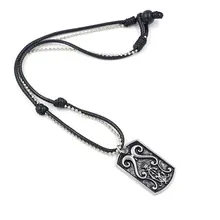 Detail of gothic scroll engraved stainless steel pendant with layered leather cord