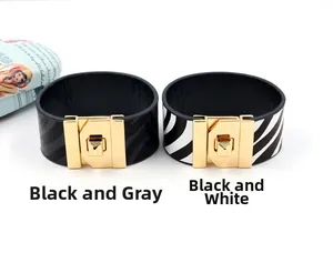 Detail van brede PU-lederen armbanden met zwart-grijze zebrapatronen en gouden gespen