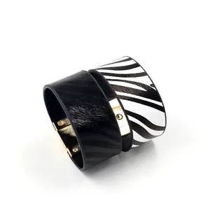 Detail van zebraprint en zwarte faux fur brede armbanden met gouden magnetische sluiting