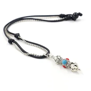 Close-up of vintage vajra pendant with turquoise bead and braided cord necklace detail