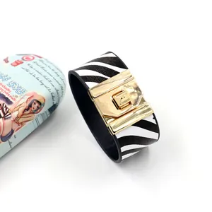 Detail van een brede zebra print lederen armband met luxe gouden metalen gespsluiting