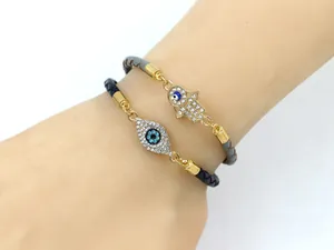 Vue détaillée de bracelets en cuir tressé avec main de Fatma et breloques œil maléfique