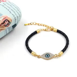 Détail d'un bracelet en cuir tressé avec breloque œil porte-bonheur dorée et cristaux