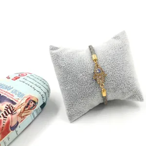 Détail du bracelet en cuir tressé gris avec main de Hamsa et œil bleu serti