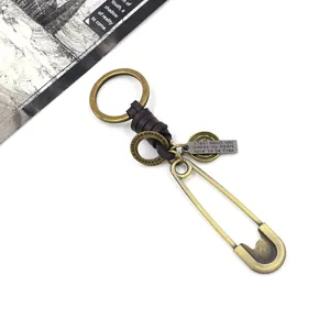 Close-up of vintage bronze safety pin keychain with brown leather wrap and engraved tags