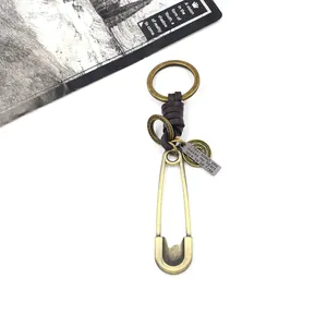 Detail of vintage bronze safety pin keychain with hand-woven dark brown leather accents