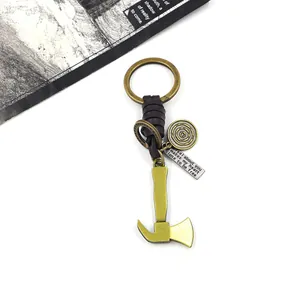 Detail of vintage bronze axe keychain with woven leather strap and engraved metal tags